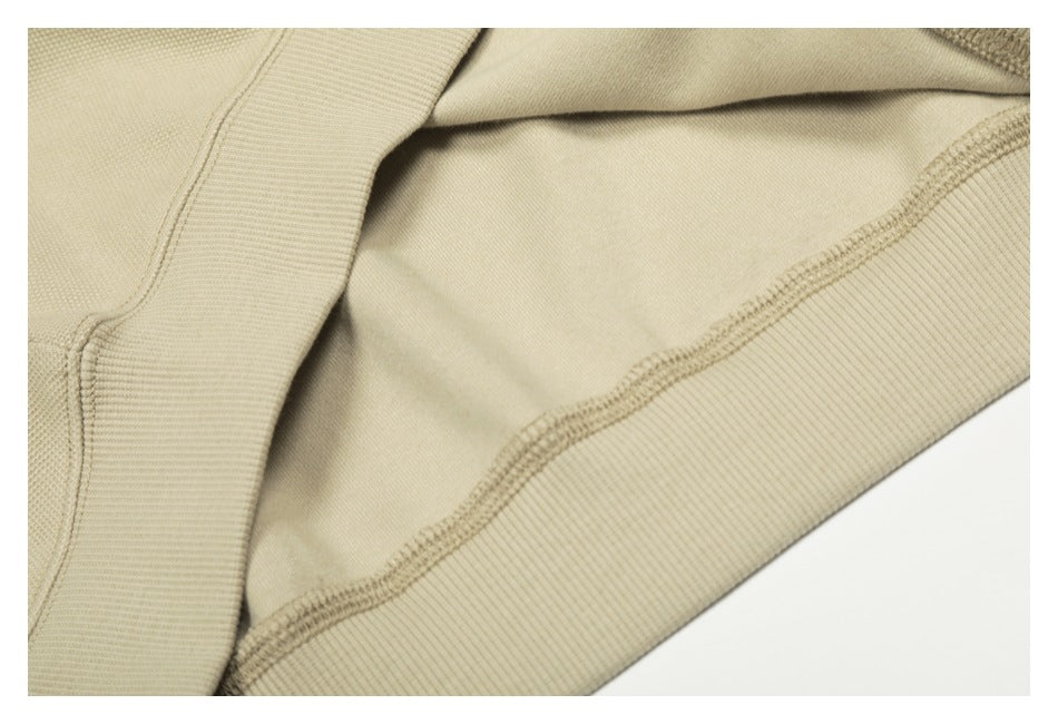 Close-up of the inside of a beige garment, showing the ribbed hem and overlocked seam.