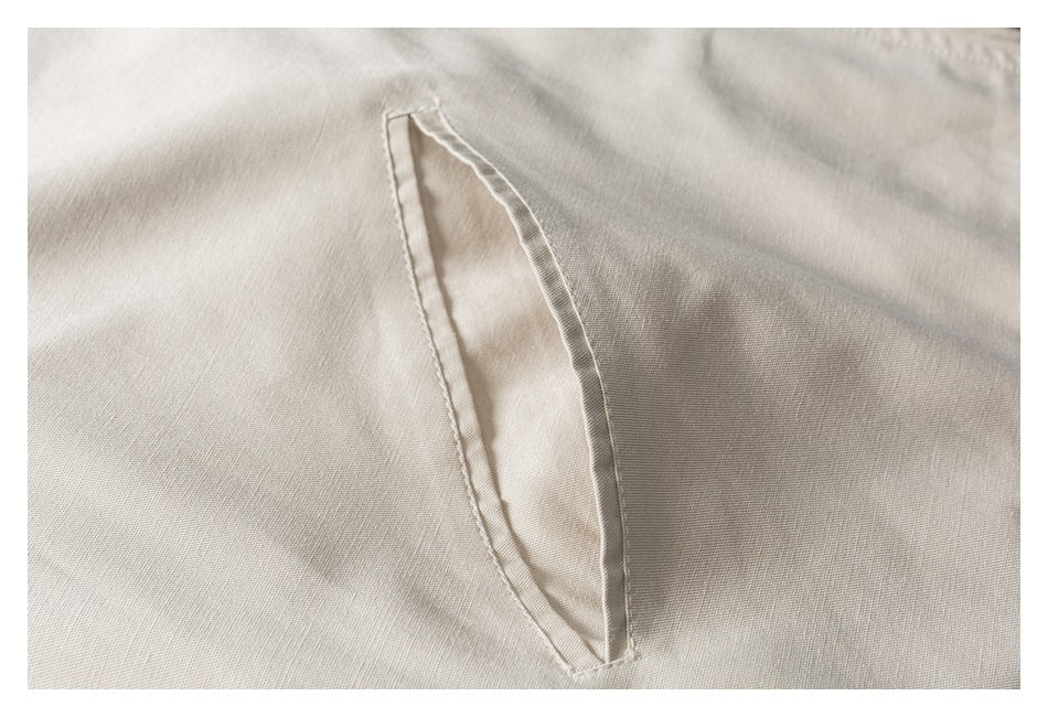 Close-up of a narrow welt pocket opening on light beige garment fabric.