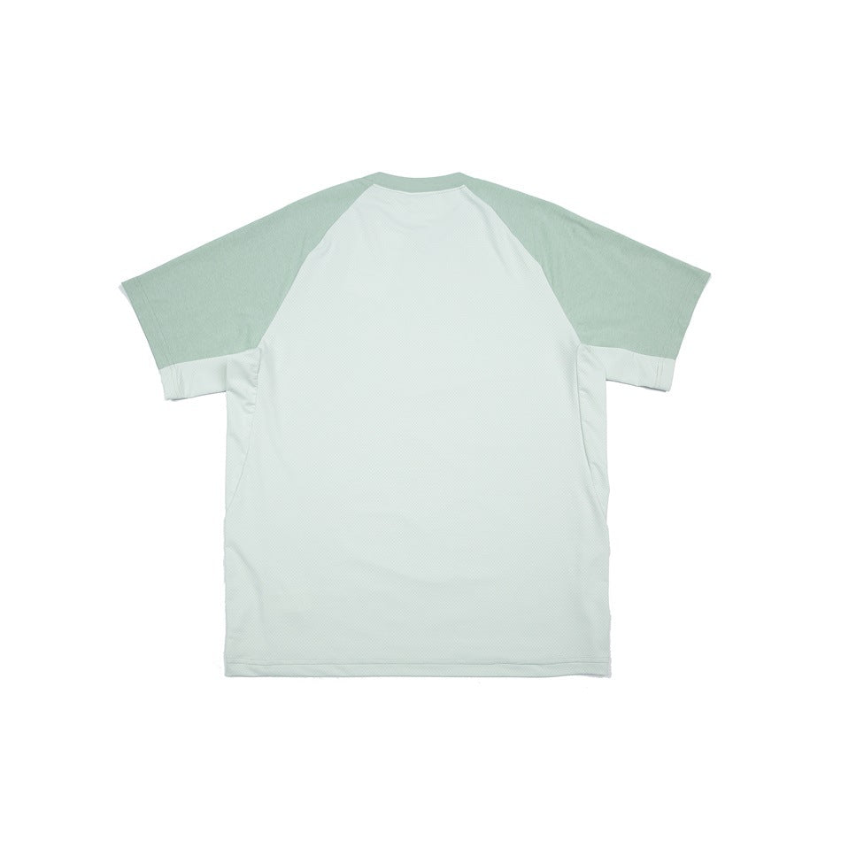 Back view of a pale mint shirt with a light body, sage-green raglan sleeves, and contrasting side panels.