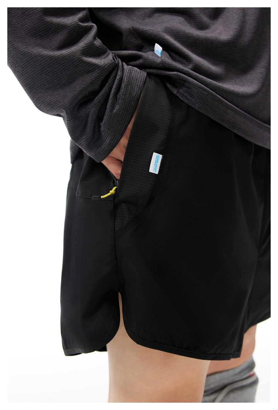 Close-up of black athletic shorts showing the textured zip pocket and small sewn labels.