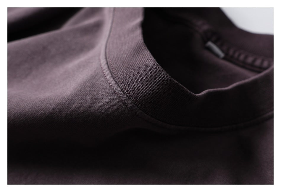 Close-up of the dark plum shirt's ribbed crew neckline and shoulder stitching.