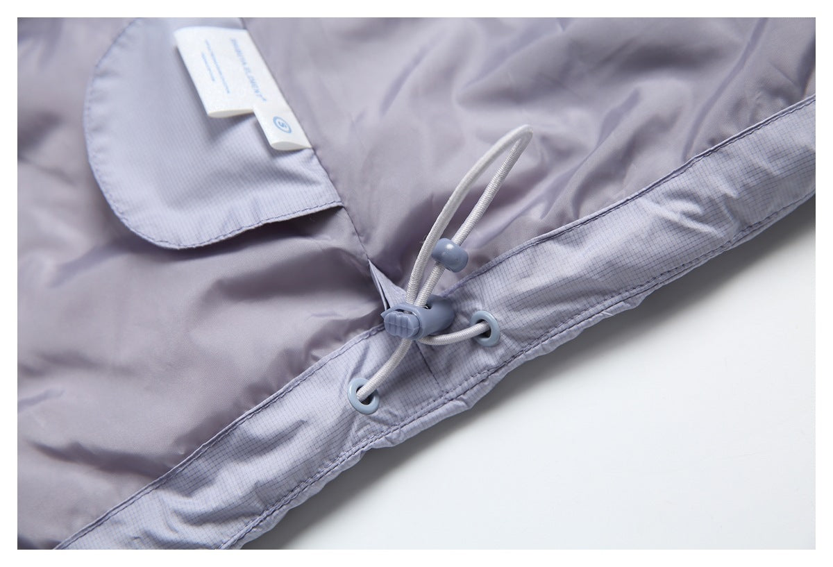 Close-up of a light lavender-gray garment hem with adjustable drawcord hardware and a small label.
