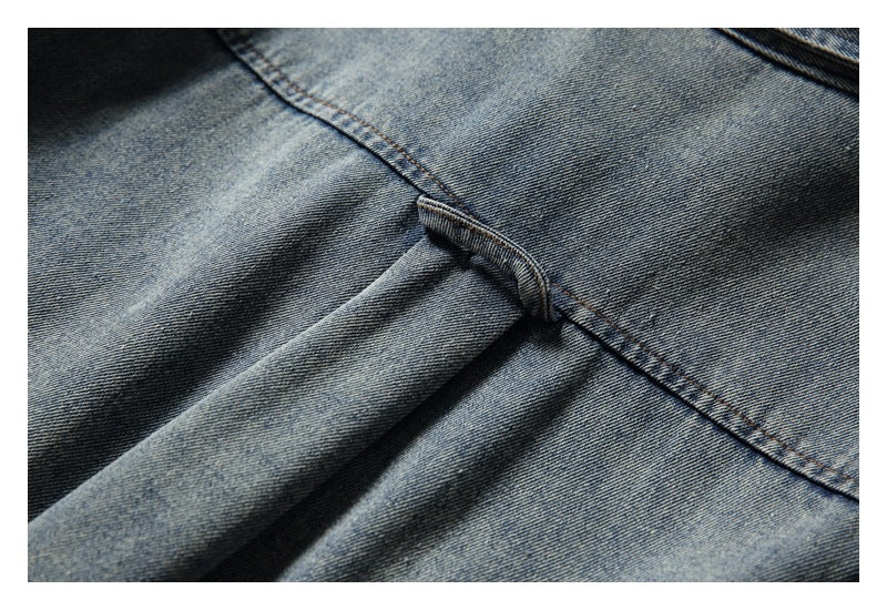 Close-up of the back yoke seam and center pleat on faded blue denim fabric.