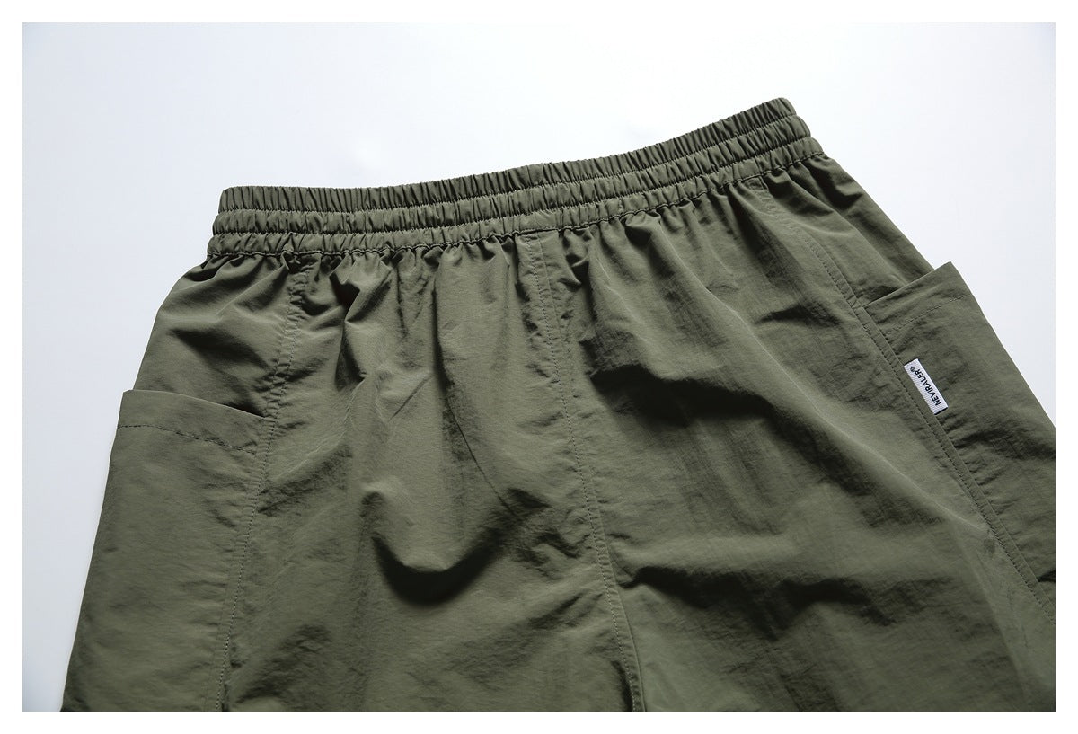 Cropped front view of dark olive shorts with a gathered waistband and large patch pockets.
