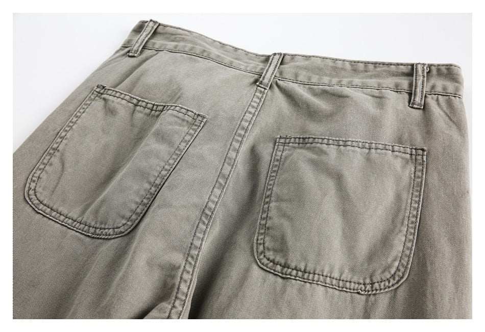 Close-up of gray-olive trousers showing two rear patch pockets, belt loops, and visible stitching.