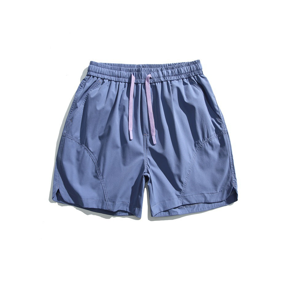 Blue drawstring shorts with lilac drawstring, elastic waistband and curved split hem, flat front view