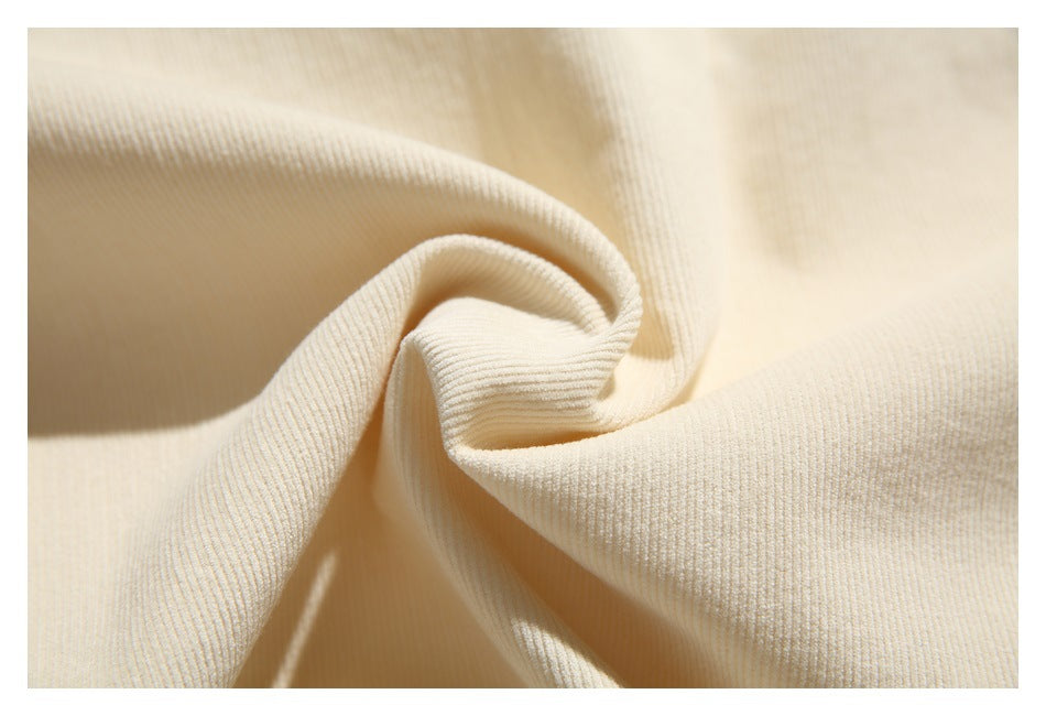 Close-up of ivory ribbed fabric gathered into soft folds.