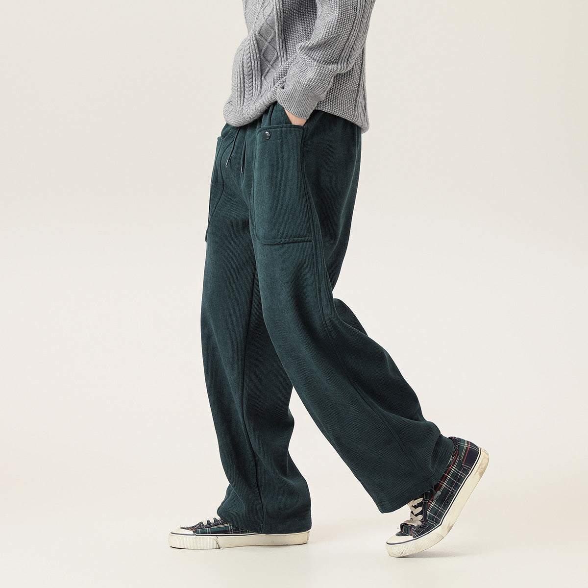 Model wearing dark teal wide-leg ribbed pants with a drawstring waist and large side pocket, shown at an angle.