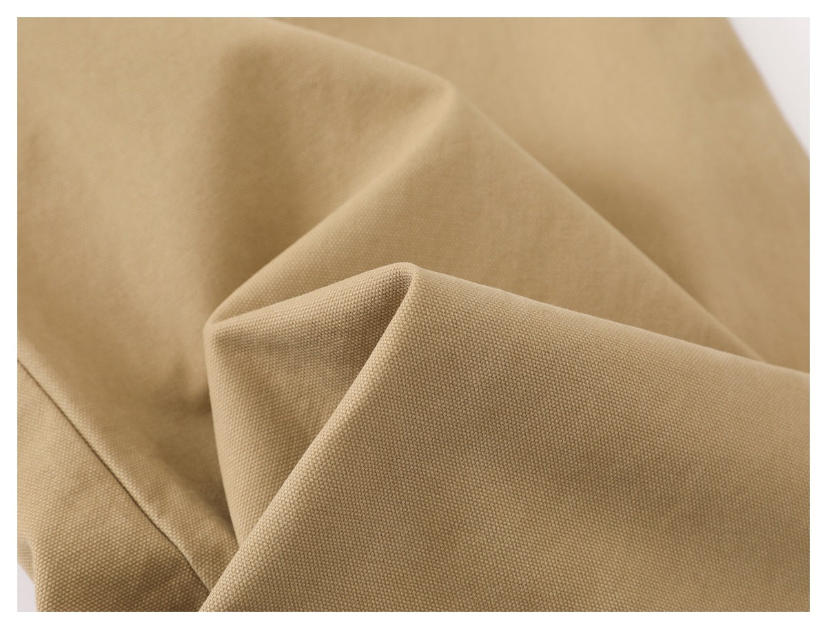 Close-up showing the textured tan garment fabric folded into soft drapes.