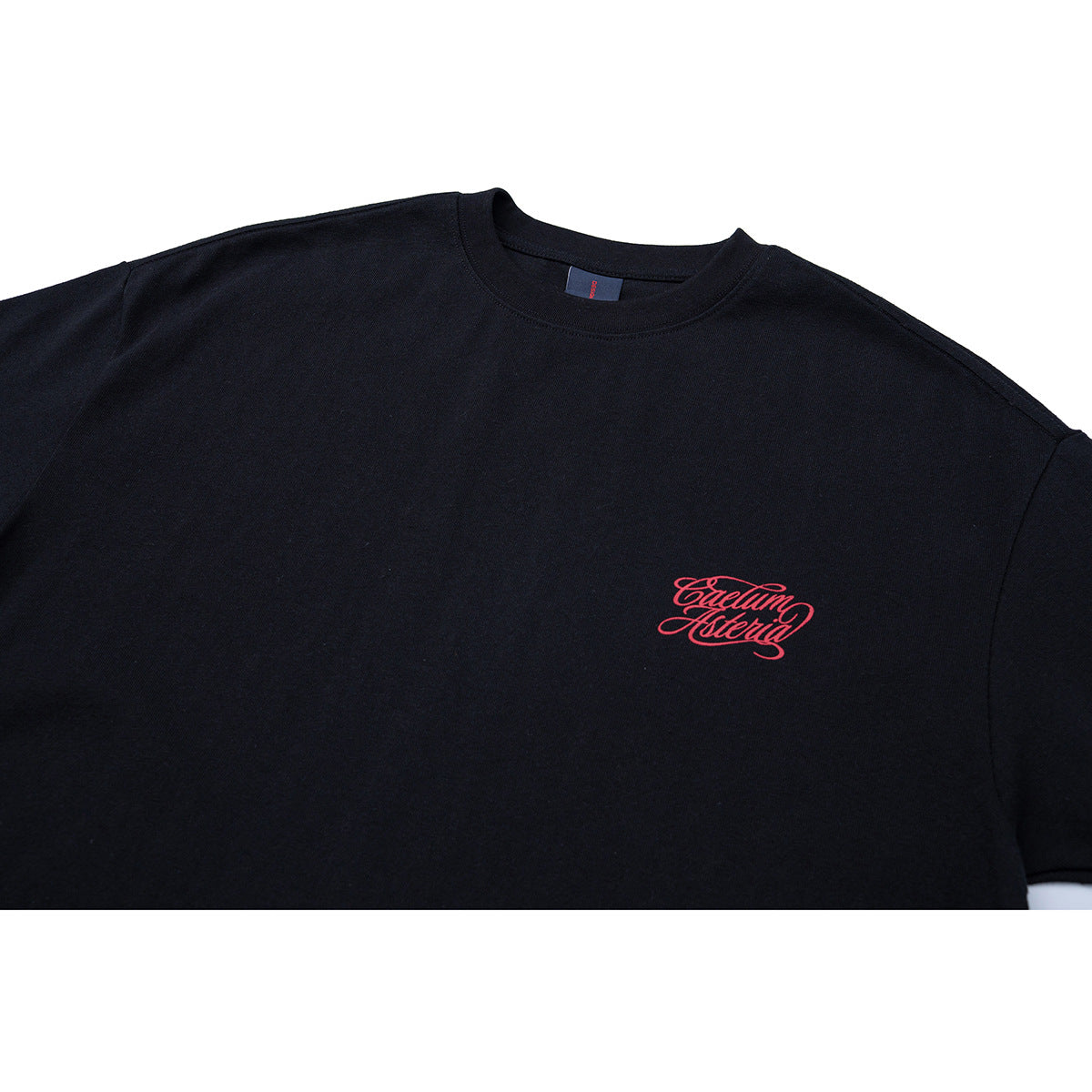 Close-up of a black crew-neck T-shirt with small red script lettering on the chest.