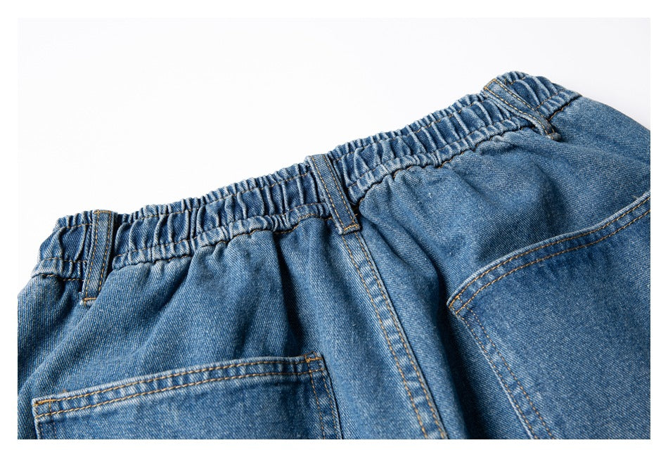 Close-up of the back of blue denim shorts with a gathered waistband, belt loops, and a rear pocket.