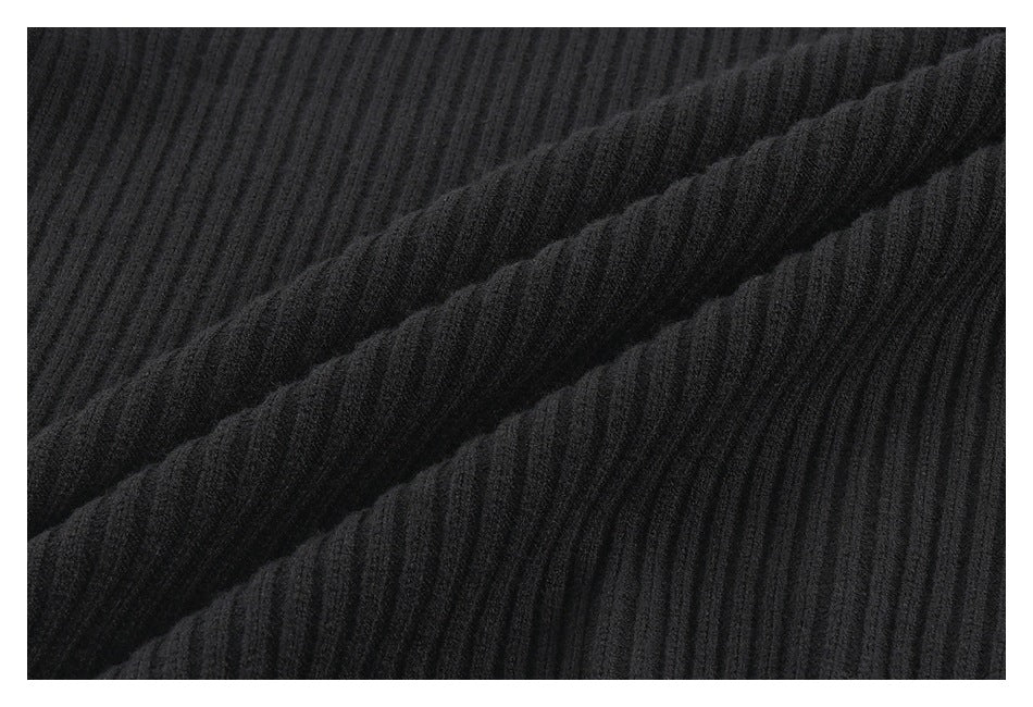 Close-up of black ribbed fabric arranged in diagonal folds, showing its raised texture.