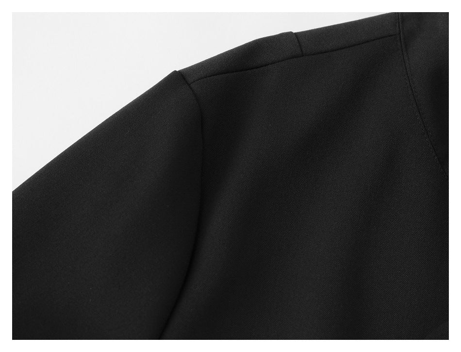 Close-up of the black jacket's shoulder seam and upper panel.