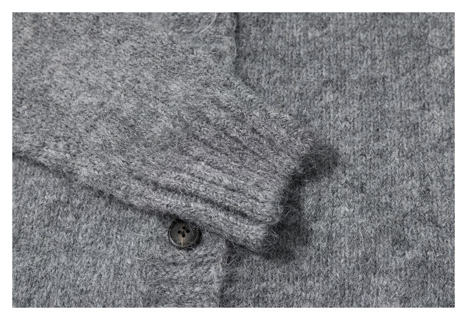 Close-up of gray cardigan knit, a folded button placket, and a dark button.