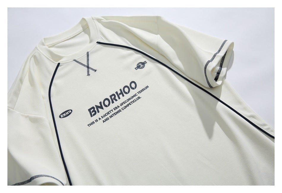 Angled close-up of the off-white T-shirt showing its dark piping, stitched details, and printed English graphics.