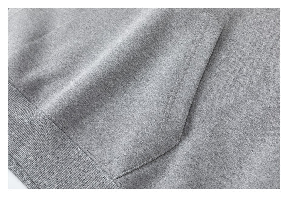 Close-up of the gray hoodie’s kangaroo pocket seam and ribbed waistband.