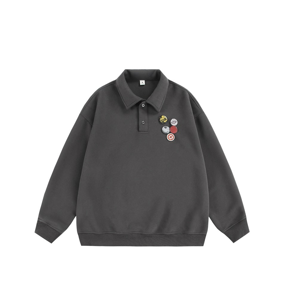 Front view of a charcoal-gray collared pullover with long sleeves, ribbed cuffs and hem, and colorful chest graphics.
