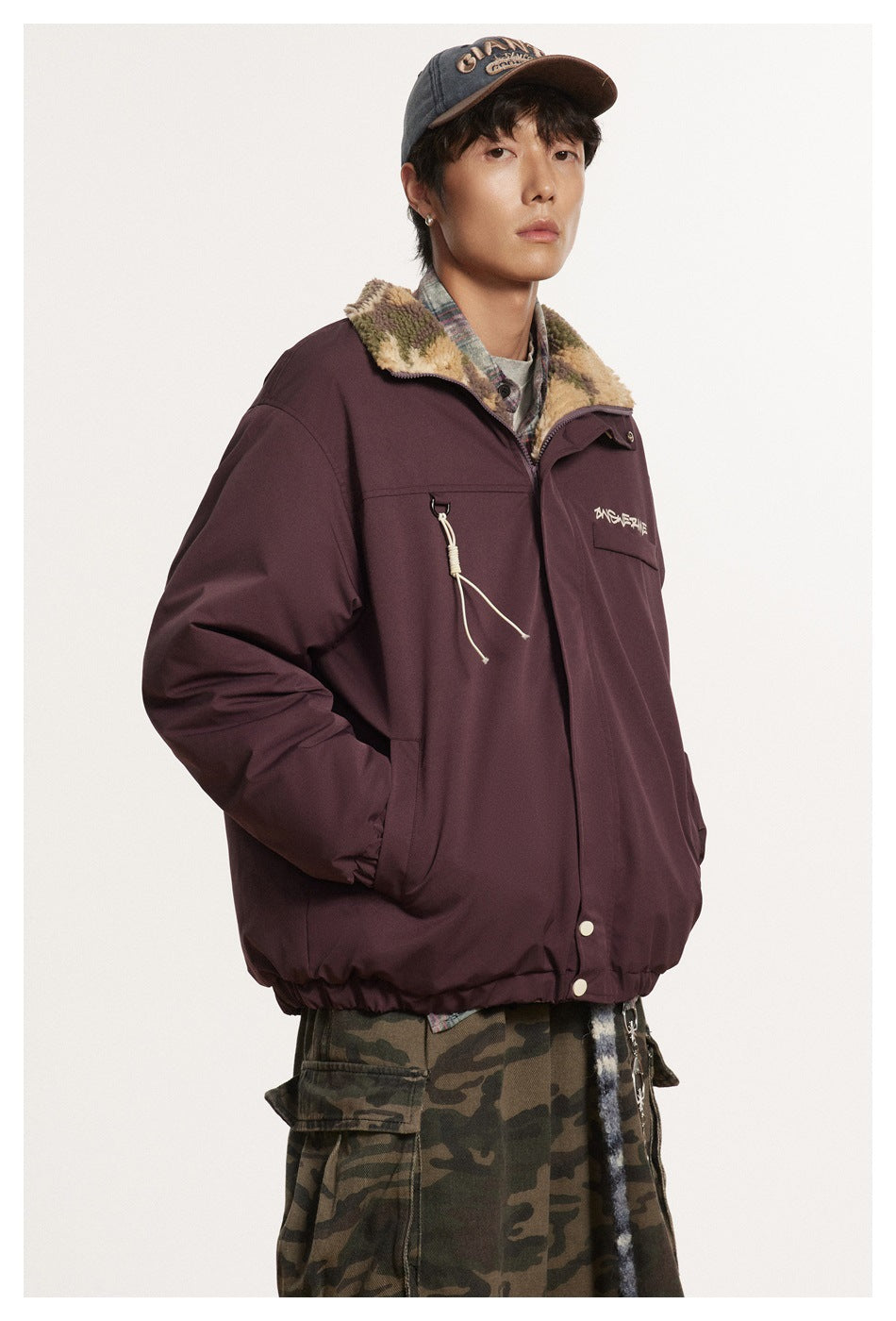 Front view of a model wearing a burgundy jacket with a camouflage fleece collar, chest pocket and drawcord detail.