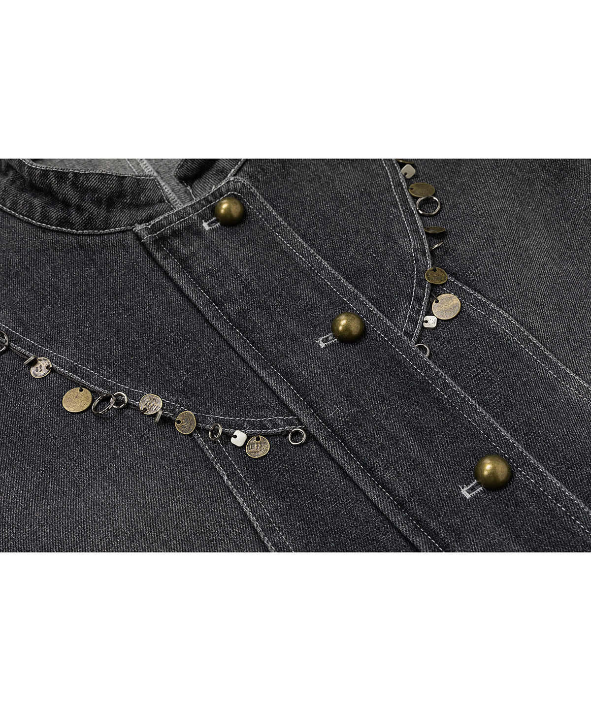 Close-up of charcoal denim jacket details: brass-tone buttons, contrast stitching, and dangling metallic disc embellishments.