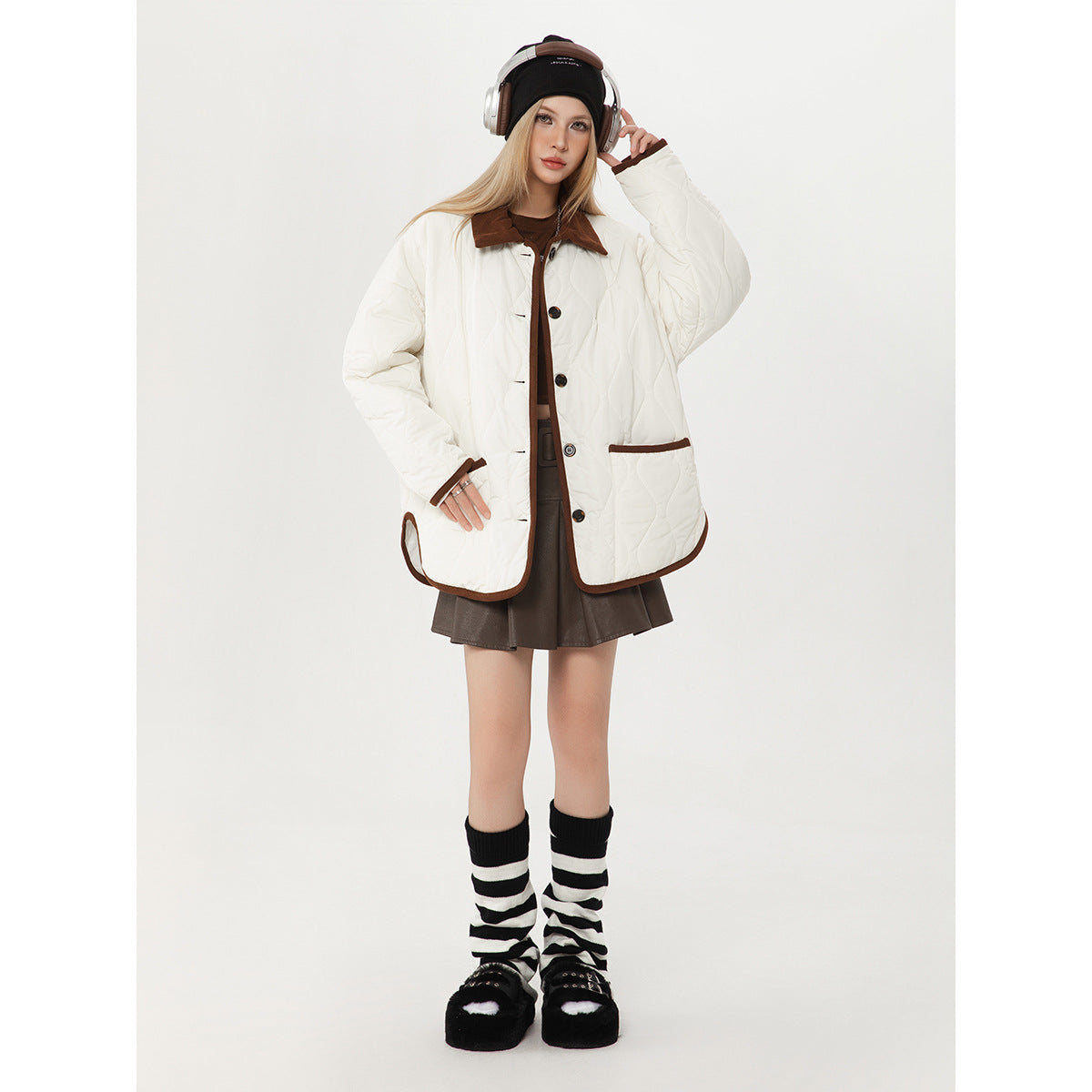 Model wearing a white quilted jacket with a brown collar, button front and brown-trimmed pockets.