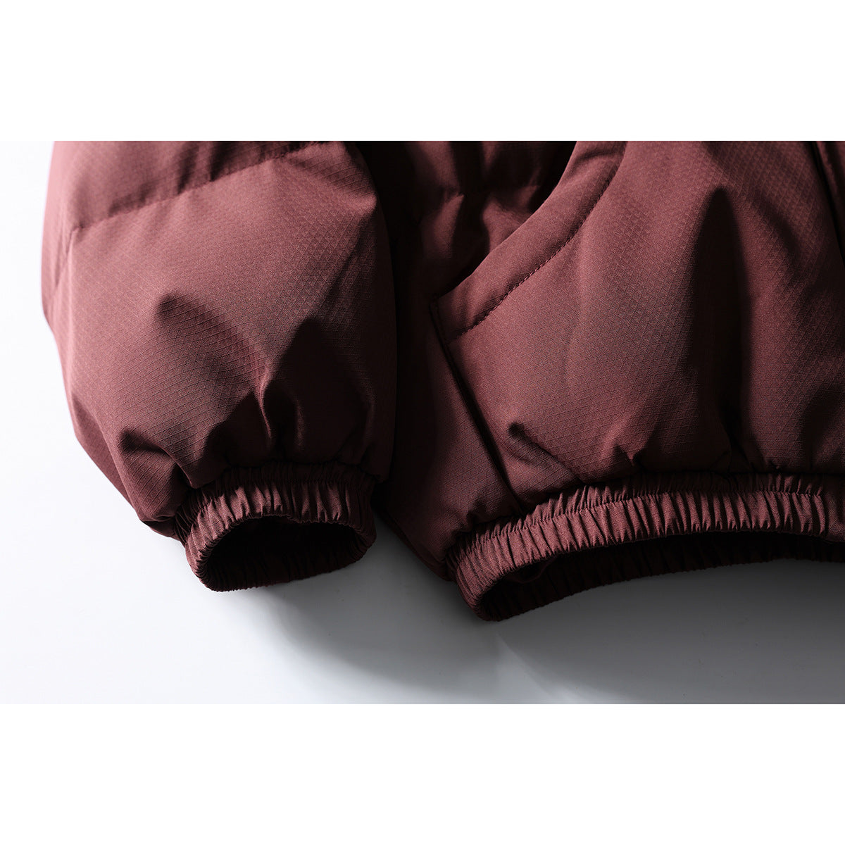 Close-up of a burgundy jacket showing its elastic sleeve cuff and gathered hem.