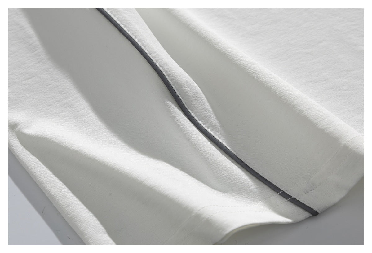 Close-up of a white garment edge with narrow dark piping and stitched hem details.