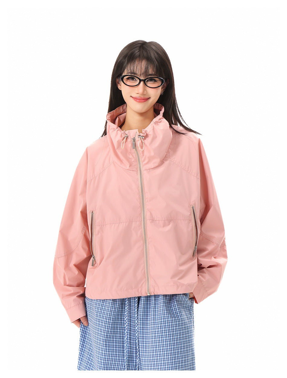 A model wears a light pink jacket with a gathered high collar, front zip, and two vertical zip pockets.