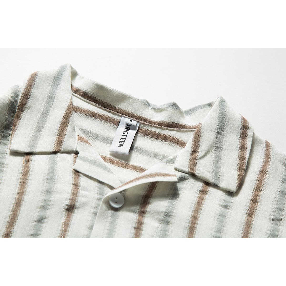 Close-up of a cream striped shirt collar, open neckline, white button, and sewn-in neck label.