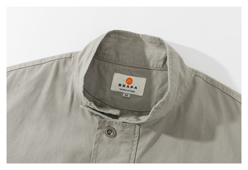 Close-up of a light khaki jacket collar and sewn neck label with an orange emblem and the text BSAPA.