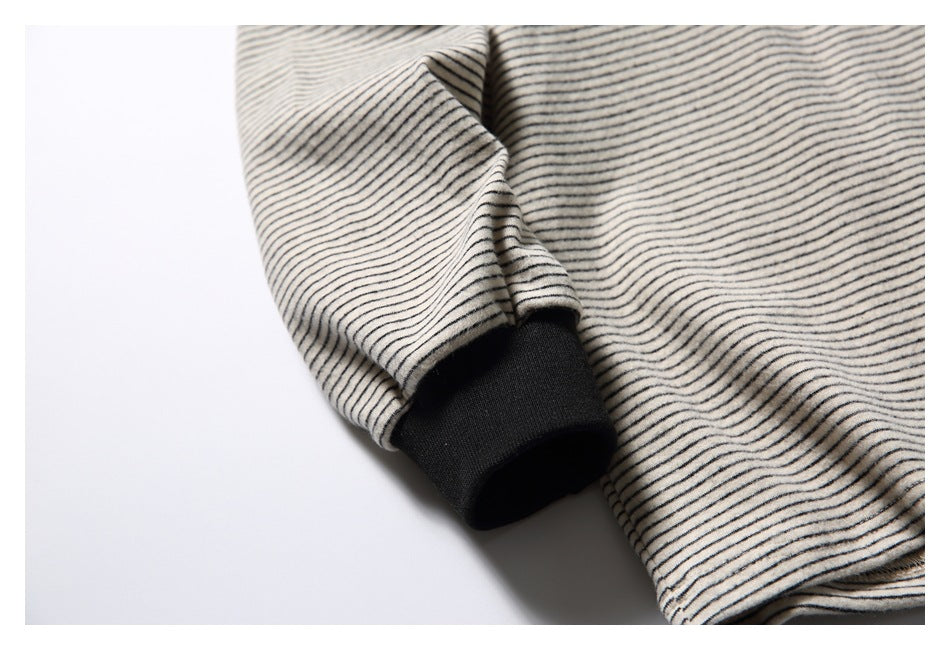 Close-up of an off-white and dark striped sleeve ending in a black ribbed cuff.