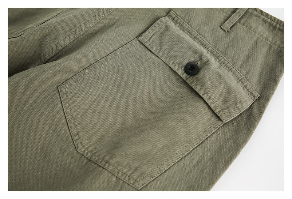 Close-up of an olive-khaki back pocket with a buttoned flap and visible stitching.