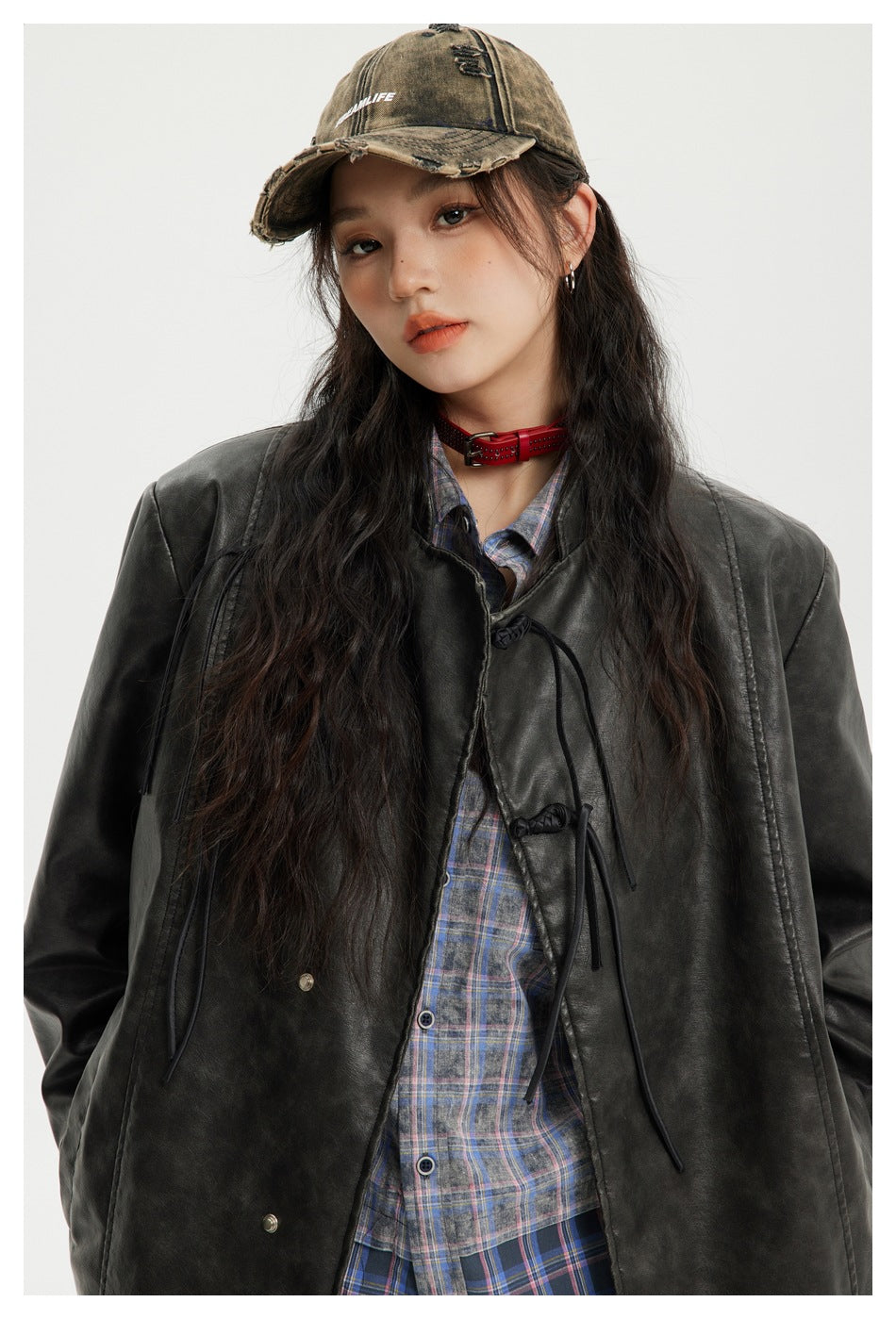 Close view of a model wearing a charcoal-black jacket with frog closures over a blue plaid shirt.