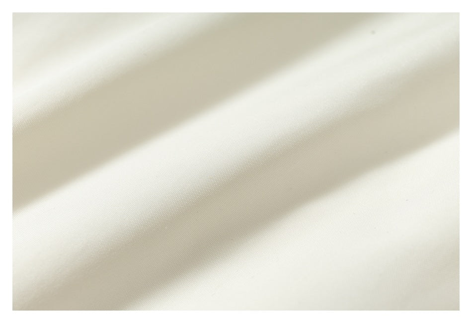 Extreme close-up of the ivory garment fabric showing its fine surface texture.