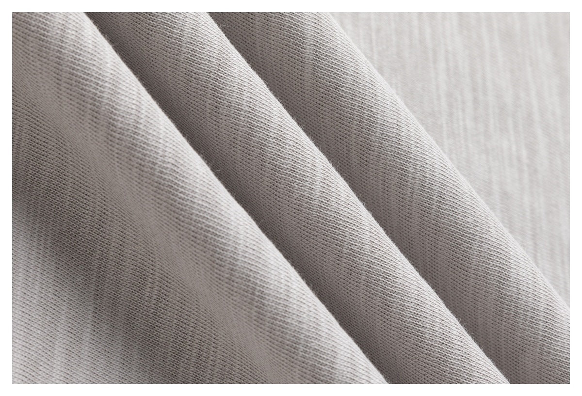 Close-up of light gray knit fabric draped in soft folds, showing its fine stitch texture.