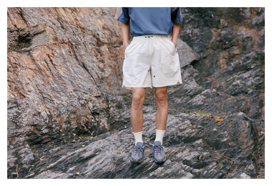 Front view of a cropped model wearing white elastic-waist shorts and a blue top outdoors.
