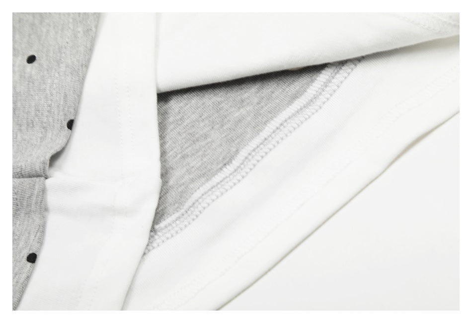 Close-up of a white stitched edge beside gray fabric with black polka dots.