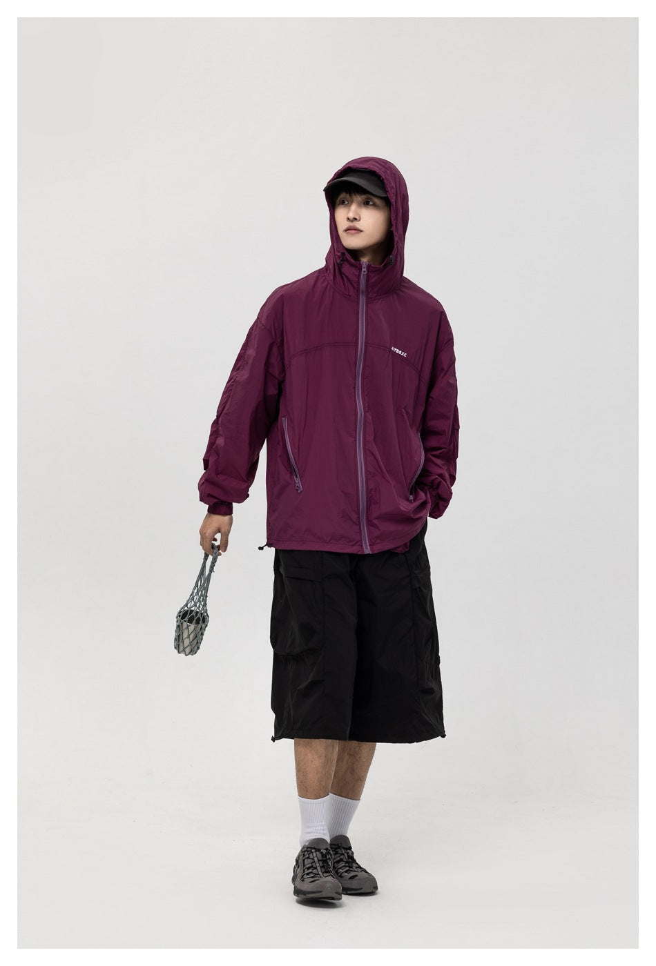 Full-length model wearing the plum hooded jacket with black shorts, white socks, and gray shoes.