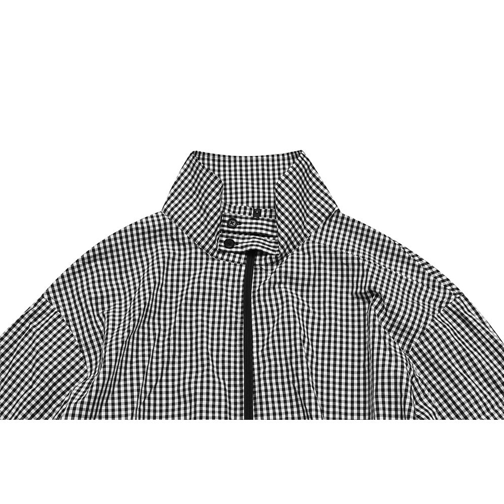 Close-up of a black-and-white gingham jacket front, showing its tall collar, button tab and black zipper.