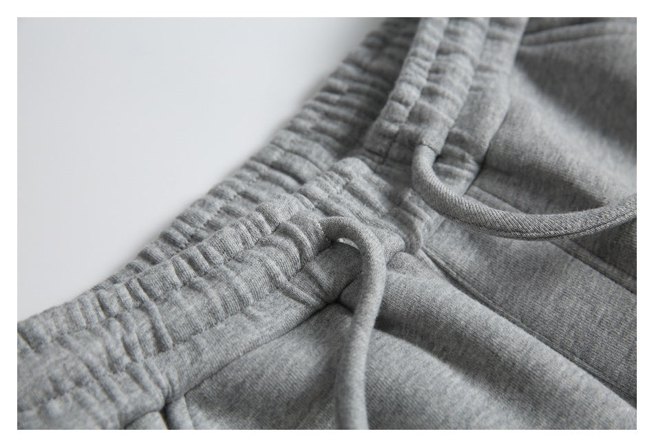 Close-up of the gathered elastic waistband and drawstring on gray sweatpants.