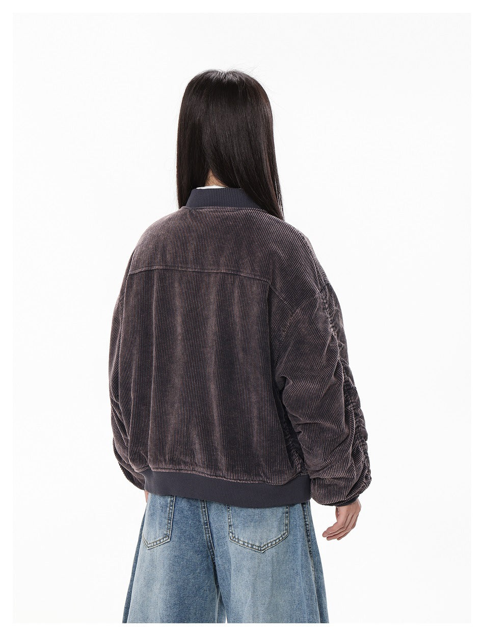 Back view of a model wearing a dark brown ribbed bomber jacket with a ribbed hem and blue jeans.