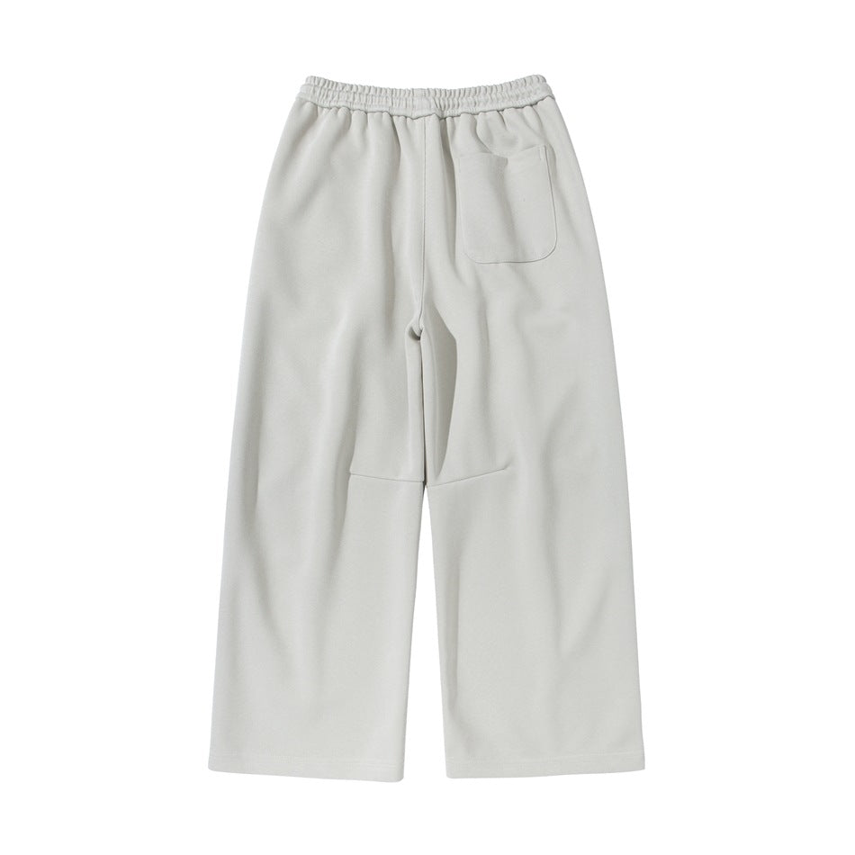 Light beige wide-leg pants back view with elastic waistband, one patch pocket and a seam below the knee