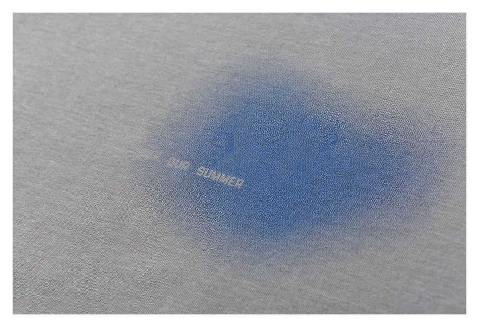 Close-up of a gray T-shirt with a blue graphic and small light-colored lettering.