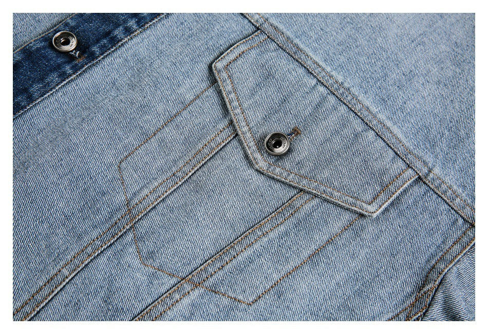 Close-up of light blue denim with a flap pocket, dark metal buttons, and contrasting brown stitching.