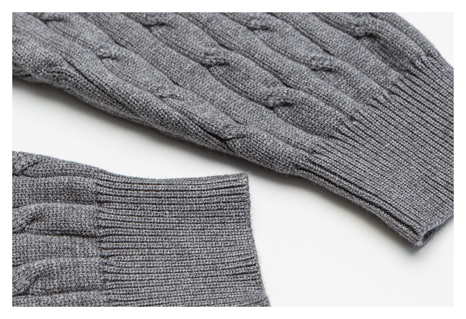 Close-up of a gray cable-knit sweater showing textured stitching and ribbed sleeve cuffs.