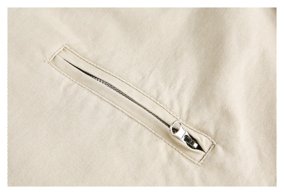 Close-up of a diagonal zippered pocket on beige jacket fabric.
