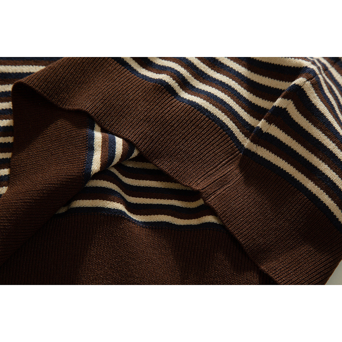 Close-up of brown ribbed cuffs and striped knit fabric in cream, brown, and navy.