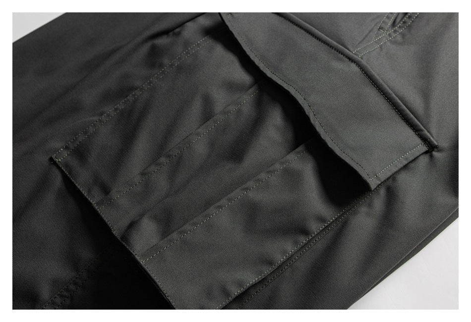 Close-up of a black garment's flap pocket and reinforced stitching.