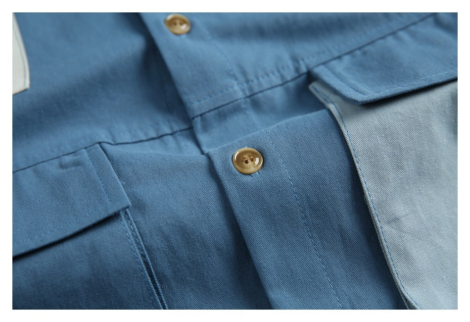 Close-up of a blue shirt front showing the button placket, tan buttons, and a flap pocket.