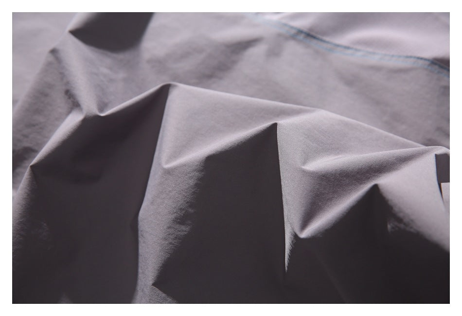 Close-up of the gray garment fabric, showing its folds and a line of blue stitching.