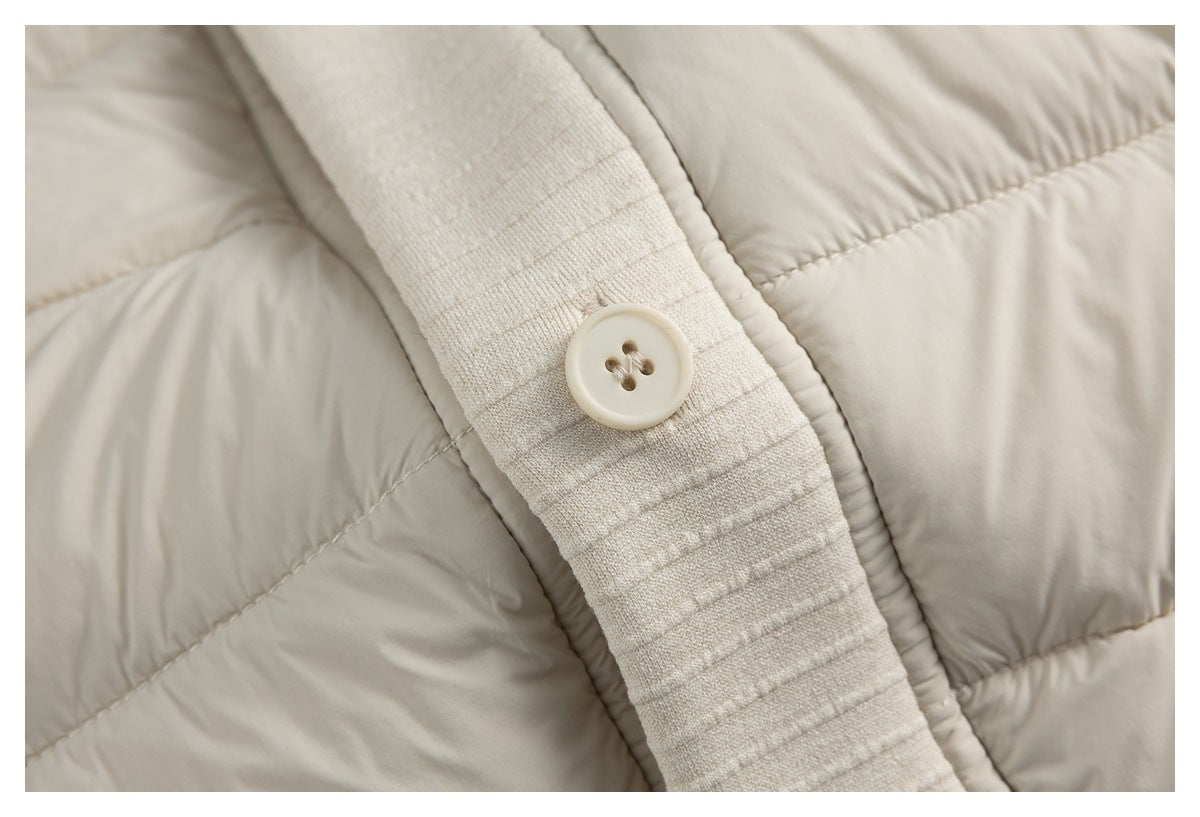 Close-up of a cream four-hole button on ribbed knit trim beside the vest's quilted panels.
